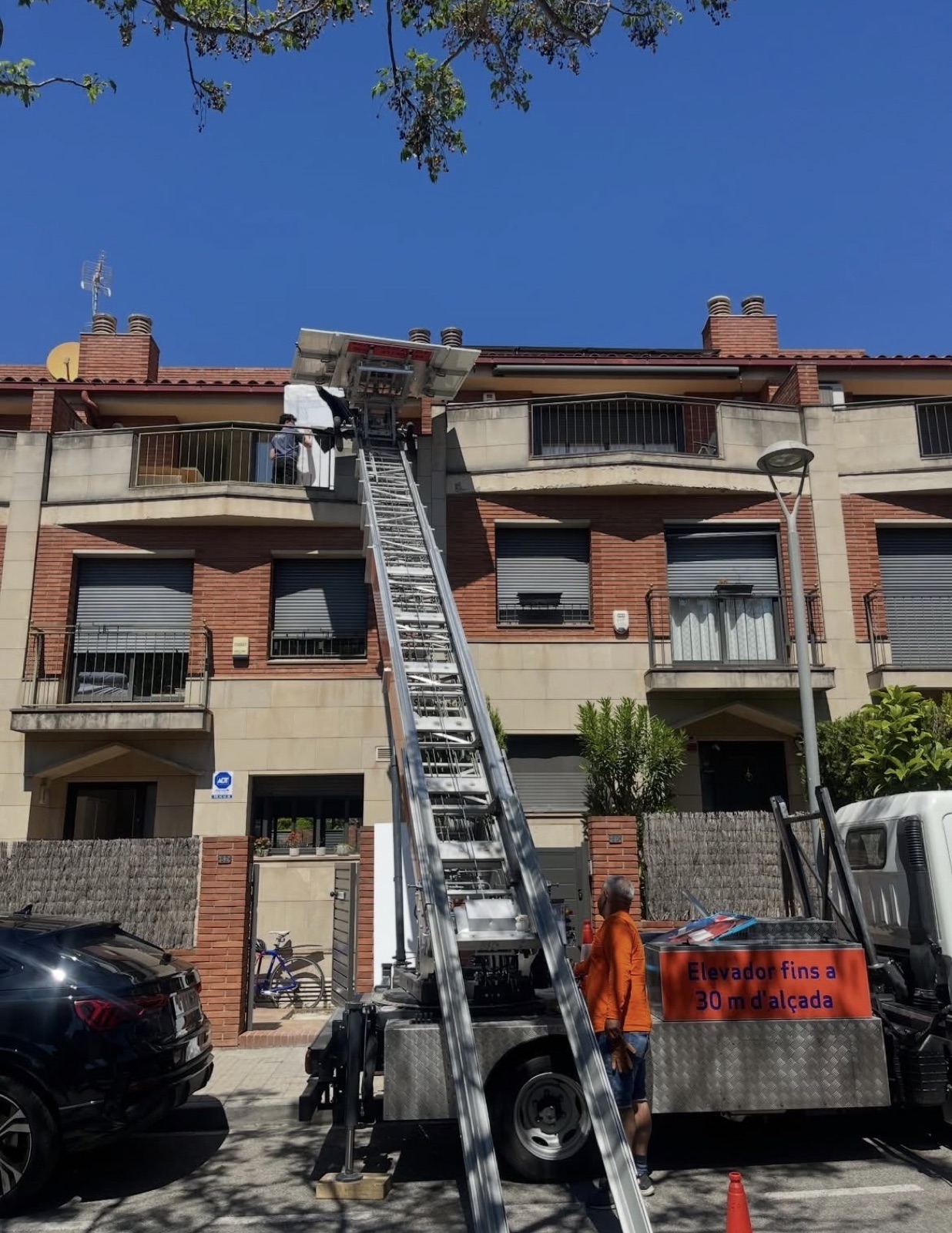 Camión con elevador de Transpro subiendo mobiliario hasta el balcón de un piso