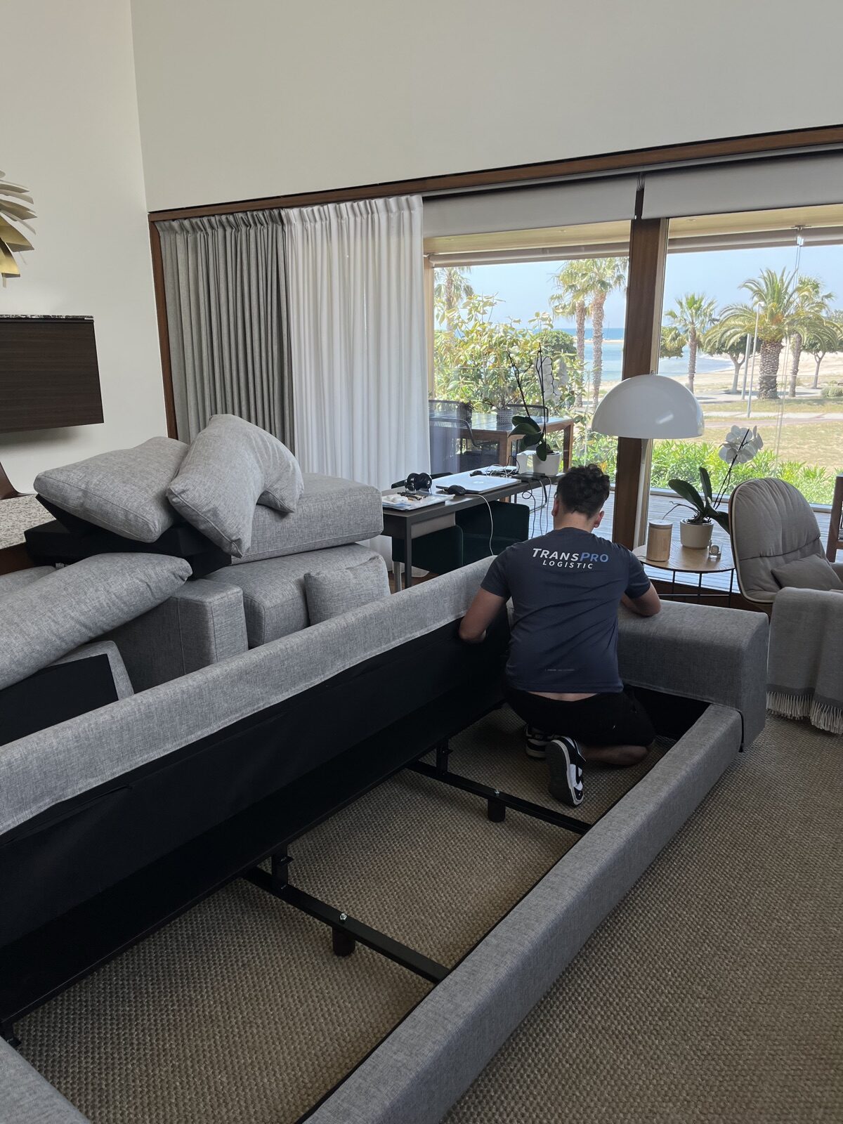Operario de Transpro montando un sofá en una vivienda con vistas al mar